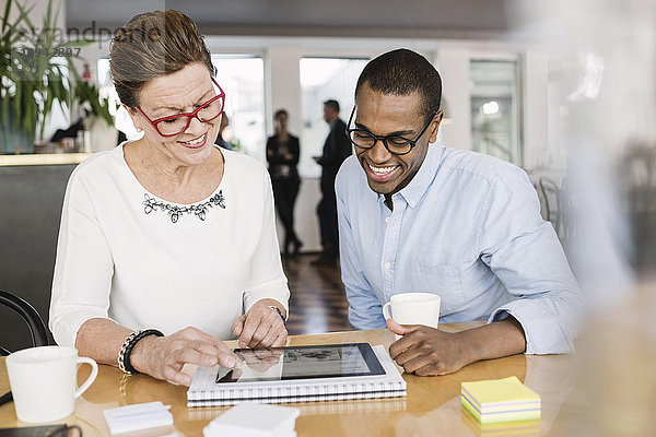 Lächelnde Geschäftsleute mit digitalem Tablett im Sitzungssaal