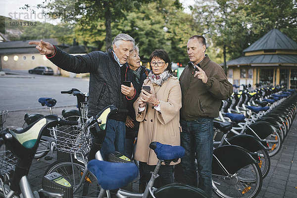 Seniorenpaare mit Mobiltelefonen am Fahrradabstellplatz