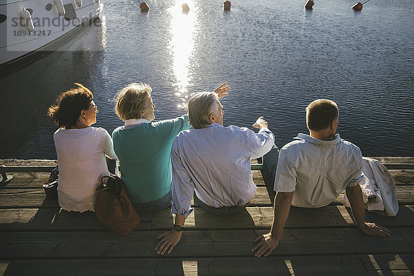 Rückansicht der Seniorenpaare  die auf dem Pier sitzen.