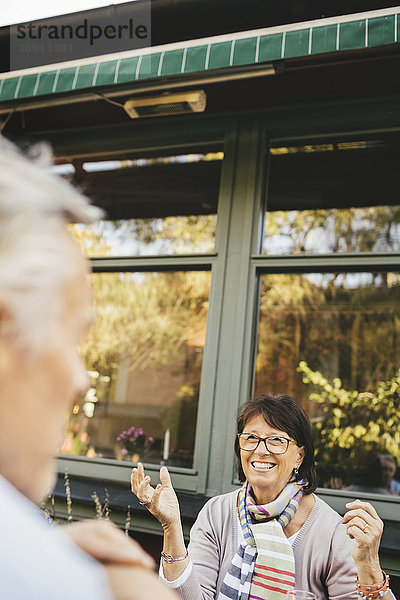 Lächelnde Seniorin mit Gesten im Outdoor-Café