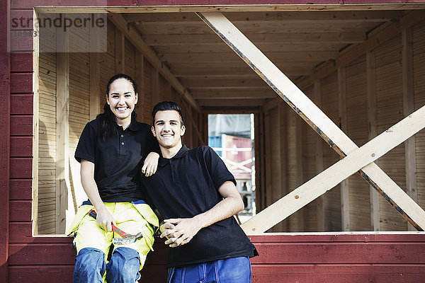 Porträt der glücklichen Schreinerei-Schüler vor der Holzhütte