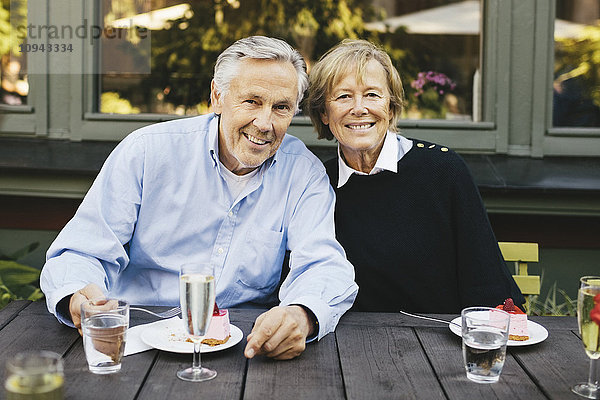 Porträt eines glücklichen Seniorenpaares beim Dessert im Außenrestaurant