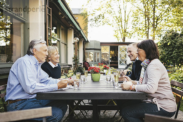 Seitenansicht von glücklichen Seniorenpaaren beim Essen im Außenrestaurant