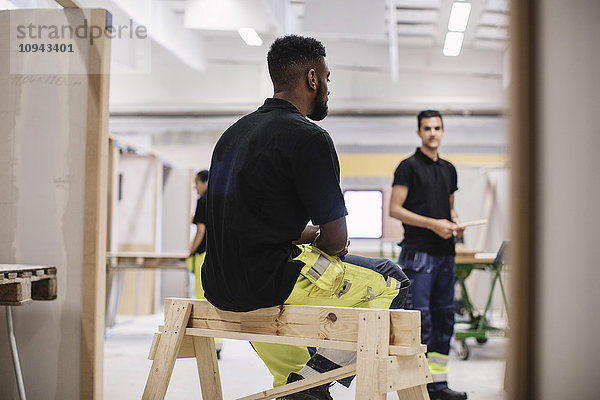 Rückansicht des Schreiner-Schülers auf Holzkonstruktion in der Werkstatt