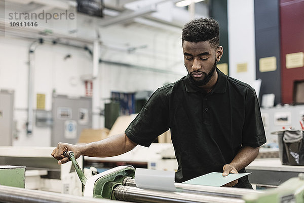 Junger Student  der die Maschine in der Werkstatt bedient