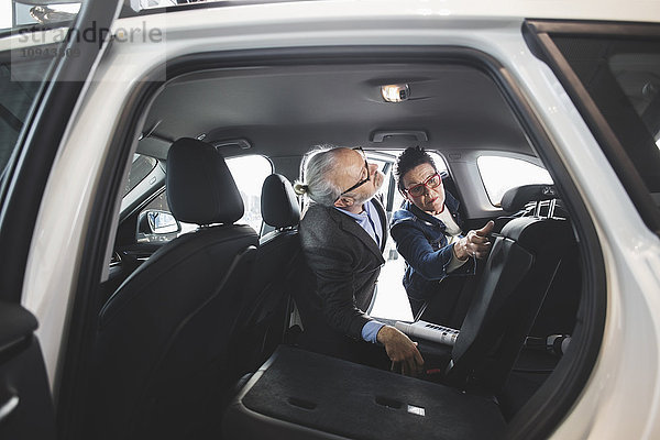 Senior Mann und Frau analysieren neues Auto im Showroom