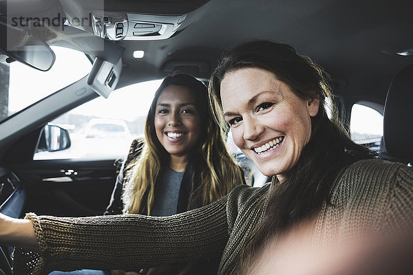 Porträt von lächelnden Freunden im Auto im Showroom