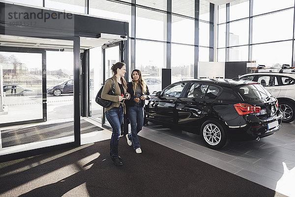 Freunde beim Betreten des Autohauses im Gespräch