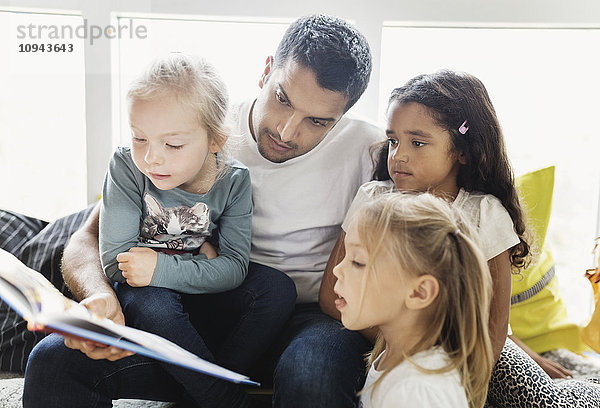 Lehrer und Mädchen lesen Geschichtenbuch in der Kindertagesstätte