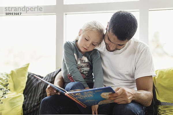 Lehrerin und Schülerin beim Lesen eines Geschichtenbuches in der Kindertagesstätte