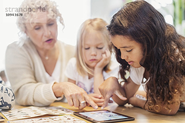 Senior Lehrerin und kleine Mädchen mit digitalem Tablett