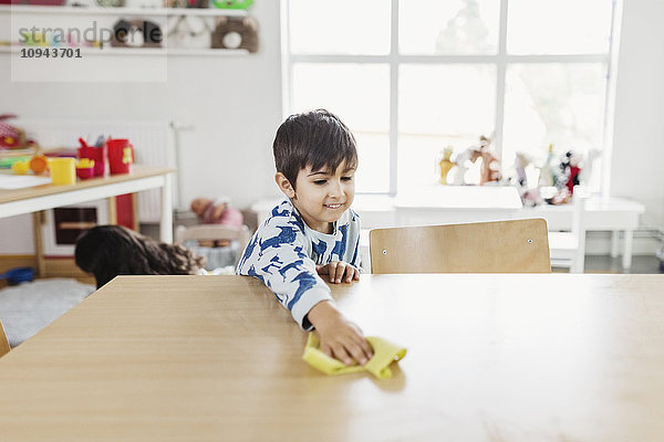 Junge Reinigung Esstisch in der Kindertagesstätte