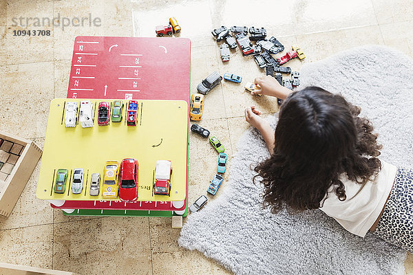 Hochwinkelansicht eines Mädchens  das mit einem Spielzeugauto in einer Kindertagesstätte spielt.