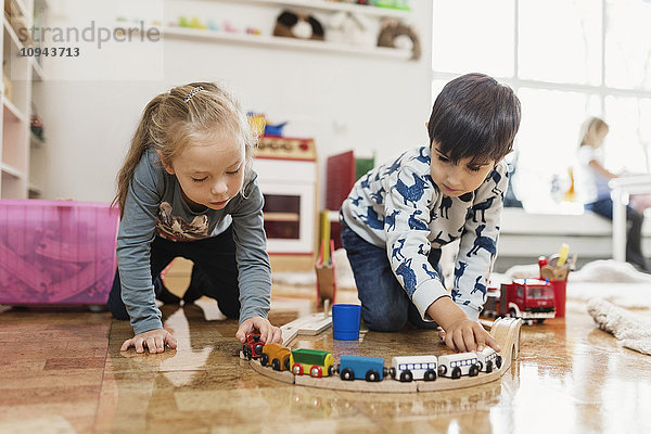 Kleiner Junge und Mädchen beim Spielen mit der Spielzeugeisenbahn in der Vorschule