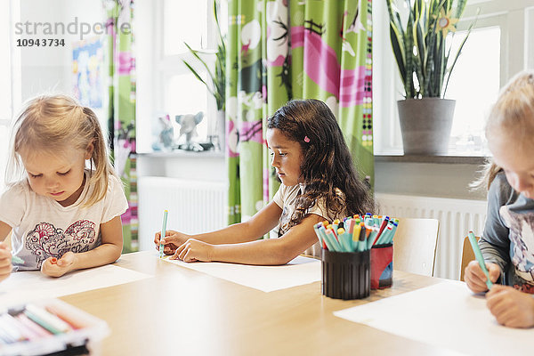 Studentinnen beim Zeichnen am Tisch im Klassenzimmer