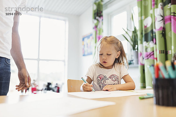 Schülerinnen beim Zeichnen am Tisch im Klassenzimmer