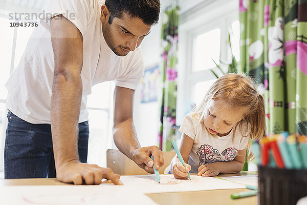 Männliche Kinder  die dem kleinen Mädchen beim Zeichnen im Klassenzimmer helfen.