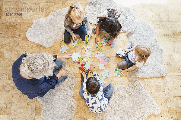 Hochwinkelansicht des Lehrers und der Kinder beim Puzzlespielen