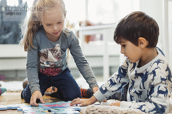 Mädchen und Junge spielen mit Puzzleteilen