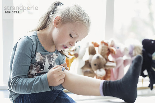 Kleines Mädchen schaut auf verletztes Knie im Klassenzimmer