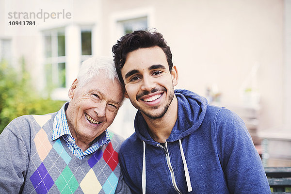 Porträt eines glücklichen älteren Mannes mit Hausmeister  der im Freien sitzt