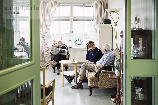 Betreuer mit Seniorenpaar im Wohnzimmer des Pflegeheims