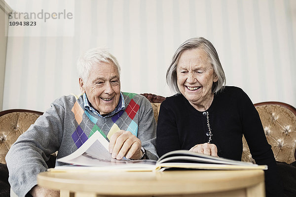 Glückliches Seniorenpaar beim Lesen im Wohnzimmer im Pflegeheim