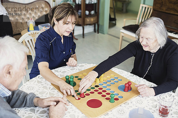 Hausmeister spielt Ludo mit Senioren im Pflegeheim