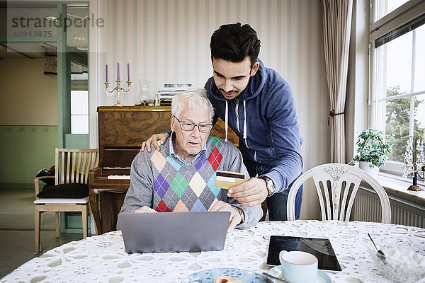 Hausmeister und Senior mit Kreditkarte im Internet einkaufen