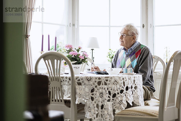Nachdenklicher älterer Mann sitzt auf dem Esstisch im Pflegeheim