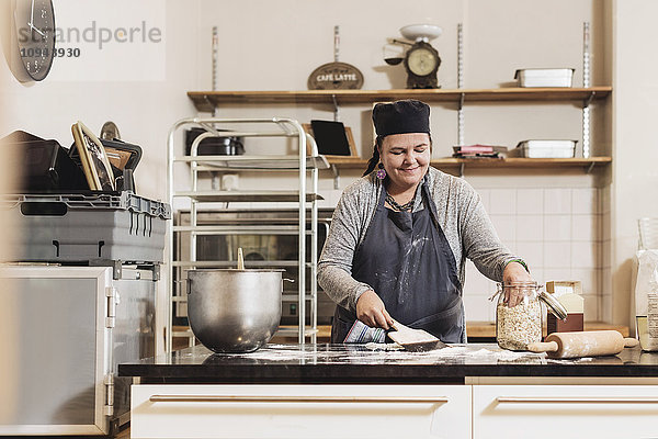 Fröhliche Bäckerin macht Teig auf der Küchentheke