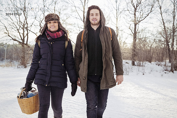 Porträt eines lächelnden Paares  das im Winter auf dem Feld spazieren geht.
