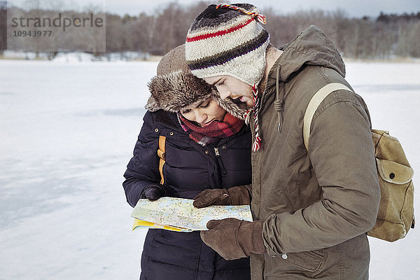 Paar  das im Winter auf dem Feld steht und sich die Karte ansieht.