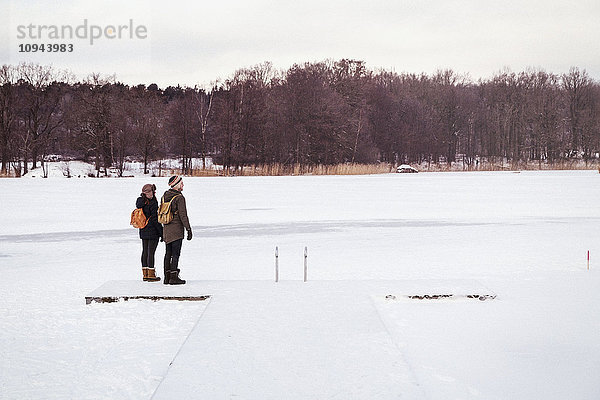 Paar steht auf schneebedecktem Feld gegen den Himmel
