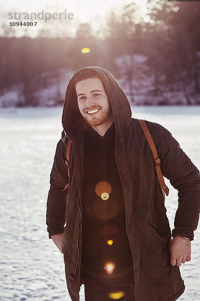 Fröhlicher Wanderer schaut weg  während er auf einem schneebedeckten Feld steht.