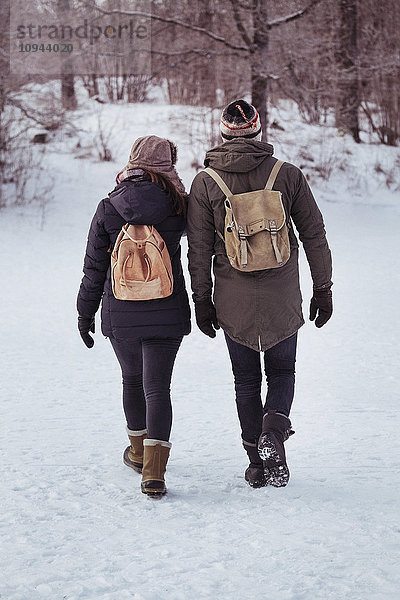 Durchgehende Rückansicht des Paares auf schneebedecktem Feld