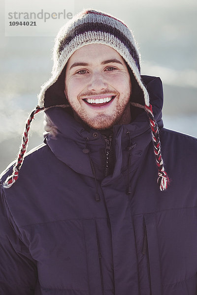 Porträt eines glücklichen jungen Mannes  der im Winter im Freien steht.