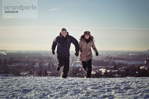 Volle Länge des glücklichen Paares auf schneebedeckten Bergen