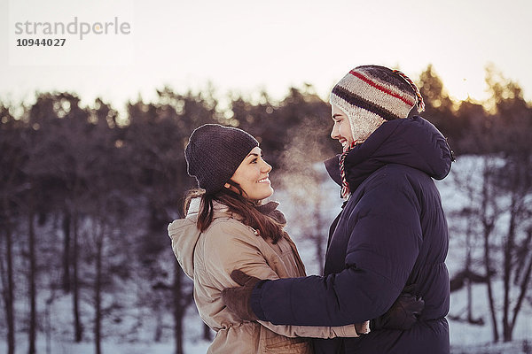 Ein glückliches Paar  das sich im Winter auf dem Feld umarmt.