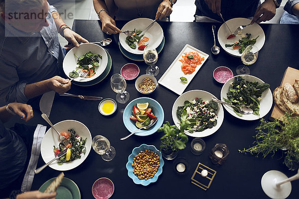 Hochwinkelansicht von multiethnischen Freunden beim Essen am Tisch