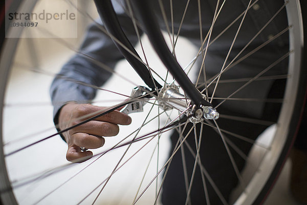 Abgeschnittenes Bild des Mannes  der das Fahrrad repariert.