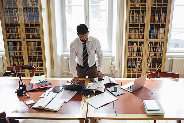 Hohe Blickwinkel auf professionelles Recherchieren im Stehen am Tisch in der juristischen Bibliothek