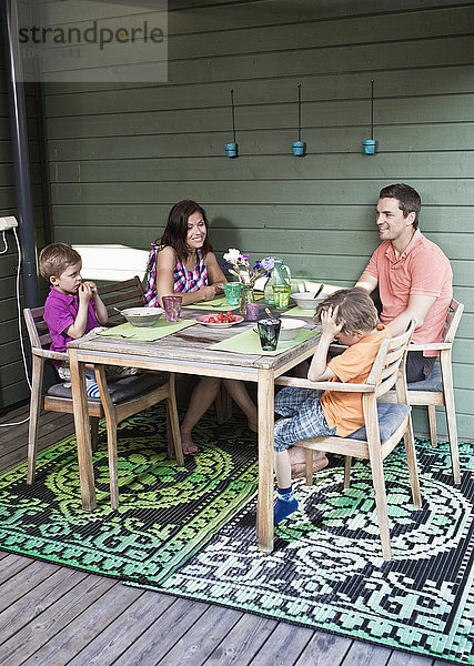 Glückliche Familie beim gemeinsamen Frühstück auf der Veranda