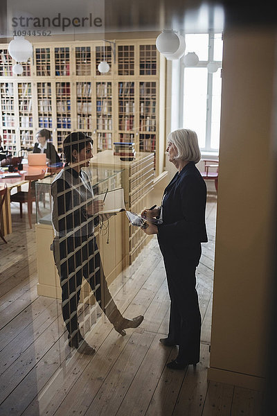 Fachfrauen diskutieren im Stehen durchs Glas in der juristischen Bibliothek