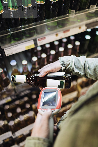 Abgeschnittenes Bild einer Kundin beim Scannen von Bierflaschen im Supermarkt