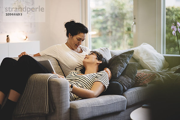 Lächelndes lesbisches Paar  das sich zu Hause im Wohnzimmer umarmt.