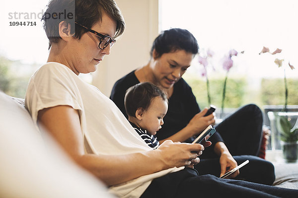 Frau mit Telefon neben Mutter und Baby mit digitalem Tablett