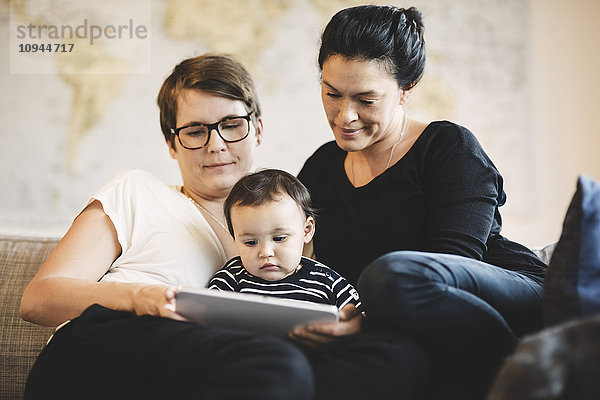 Frauen mit Kleinkind beim Sitzen zu Hause im digitalen Tablett