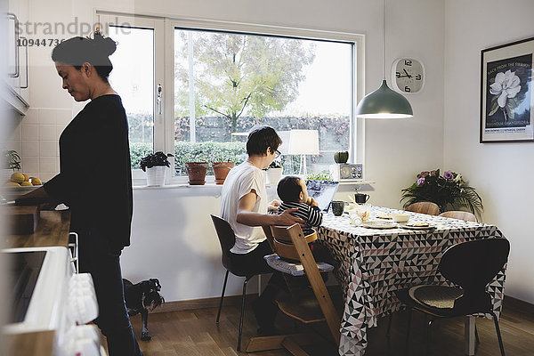 Frau arbeitet und Mutter sitzt mit Mädchen in der Küche