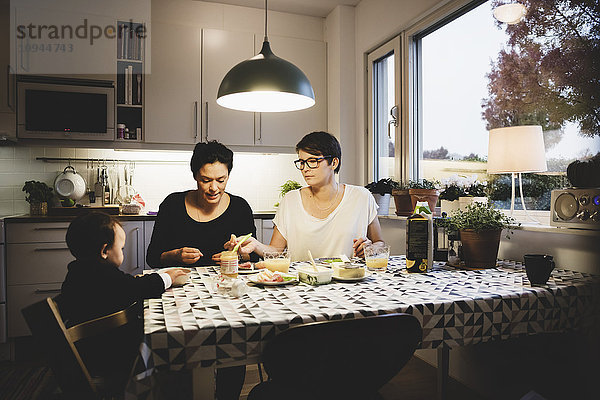 Lesbisches Paar mit Mädchen beim Essen am Esstisch